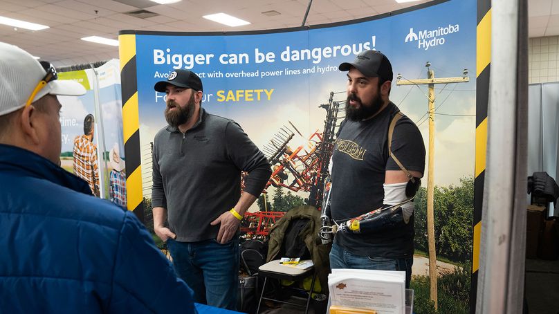 Deux membres de l’équipe de sécurité publique de Manitoba Hydro discutent avec des agriculteurs au kiosque de la Société dans le cadre des journées de l’agriculture.