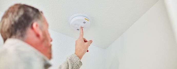 Un homme teste un détecteur de fumée.