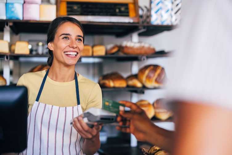 Woman working in a local bakery accepting a payment with a debit machine
