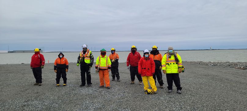 Manitoba Hydro workers who worked on the habitat pose for photo on a sandy beach.
