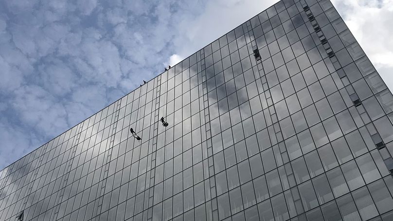 Deux hommes équipés de harnais de sécurité devant la façade du bâtiment.