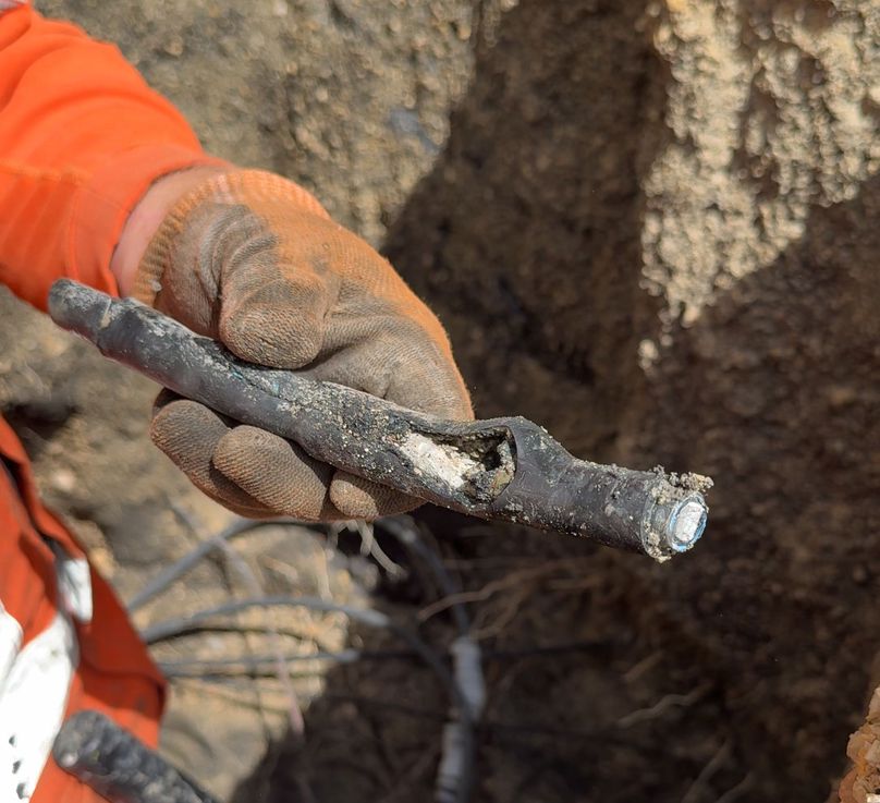 A worker holds up a section of damaged cable that they’ve cut out from the line.