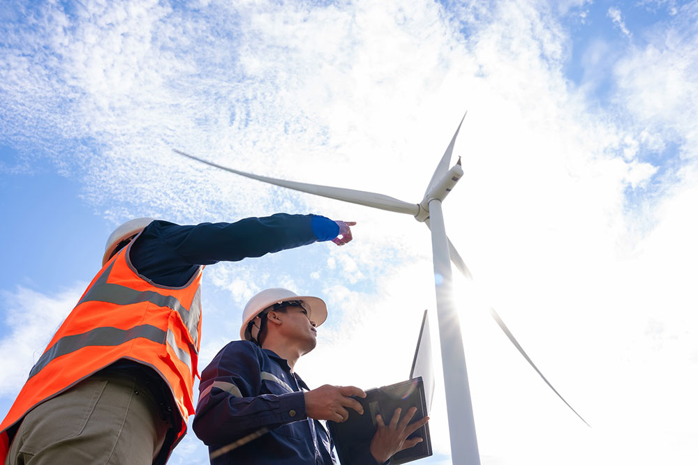 Des travailleurs se tiennent sous une éolienne