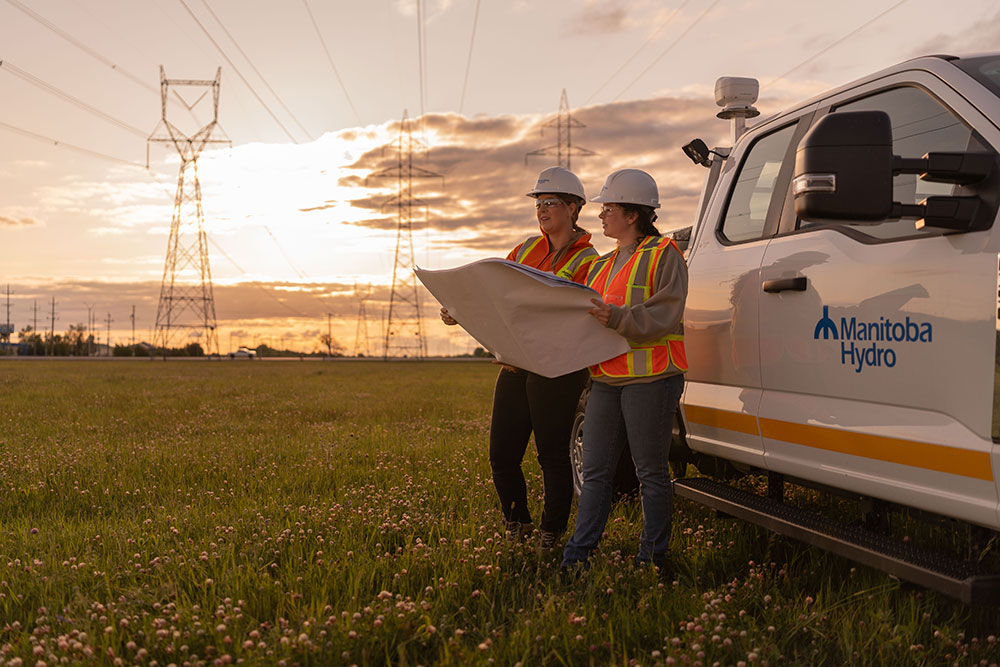 Des ingénieures sur le terrain, sous les lignes de transmission, au coucher du soleil
