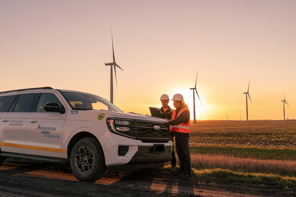 Des ingénieurs devant des éoliennes au coucher du soleil