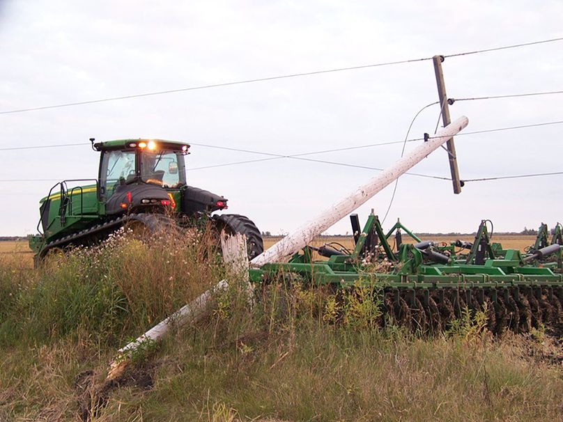 A tractor pulling a harrower onto a field knocked over a hydro pole and gets tangled up in power lines.