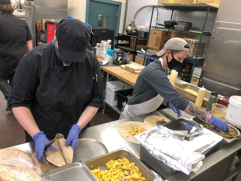 Two people prepare food in commercial kitchen.
