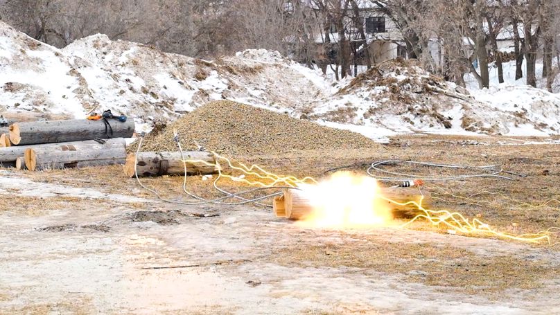 Two sets of implosion sleeves being detonated on the ground. Glowing fuses leading to a small orange sunburst and more glowing fuses headed to the next set of detonations.