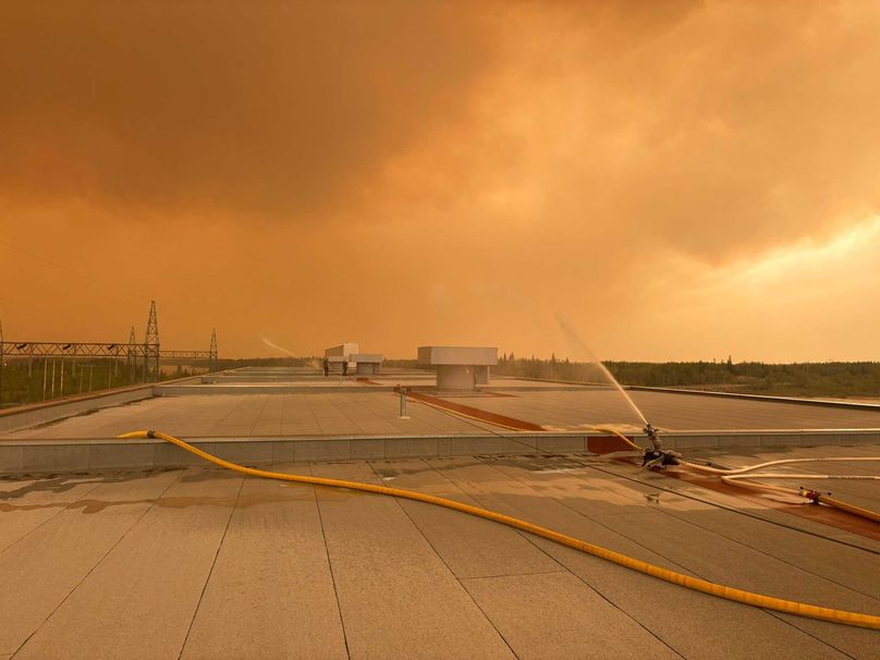 Hoses spraying water on top of a generating station roof.