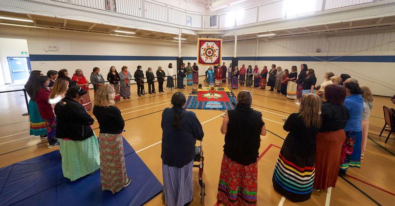 Many women stand in a circle as the leader at the top of the circle performs the ceremony.