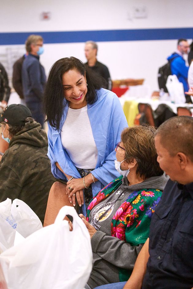 Une femme portant un châle bleu écoute une femme dans un châle à motifs partager une conversation à l’une des tables des participants.