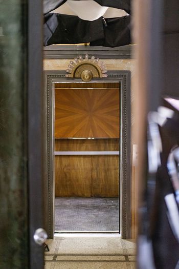 A vintage elevator at the end of a hallway.
