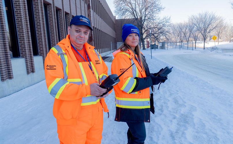 A man and woman pose in new high visibility orange jackets.