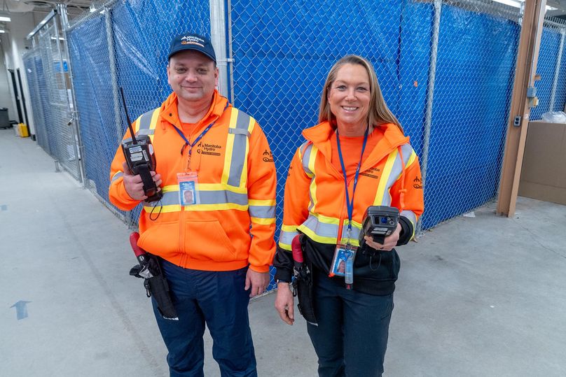 A man and a woman smile as they pose in new high visibility orange sweaters.