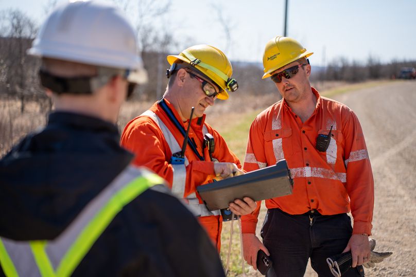 Two people in safety gear look at a clipboard.