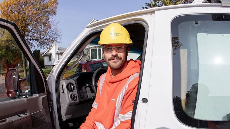 A man in high visibility clothing sits in his van with the door open.