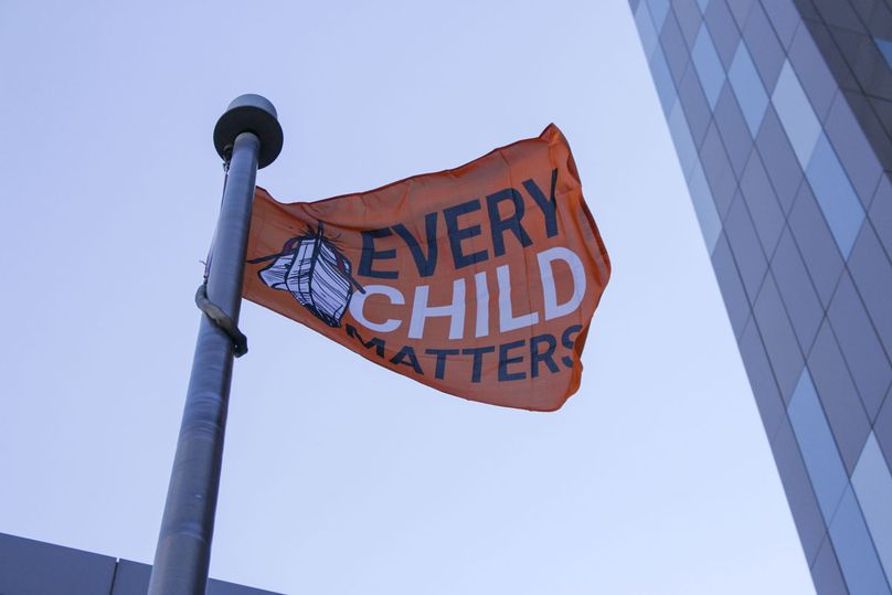 Un drapeau orange vif portant la mention Every Child Matters (chaque enfant compte) flotte au vent.
