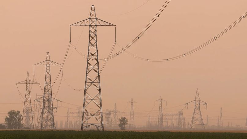 Steel transmission towers in a hazy prairie landscape.