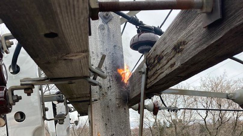 A fire burning on the cross-arm of a wooden distribution pole.