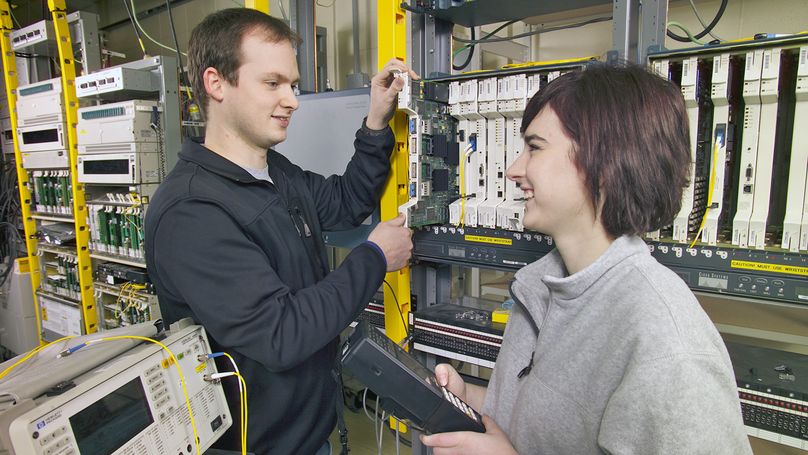 Male and female telecontrol technicians work on electronic equipment.