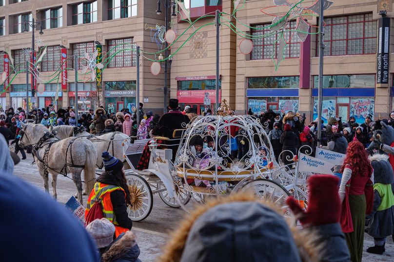 Un gros carrosse blanc tiré par deux chevaux gris.
