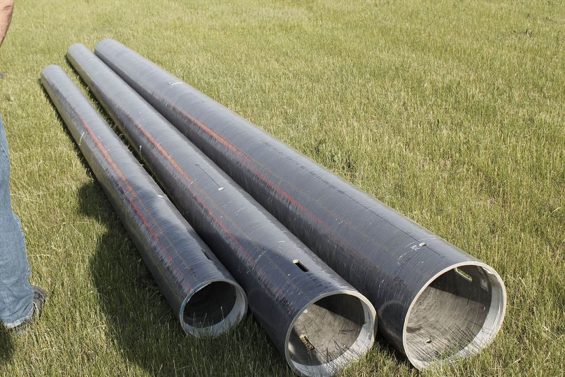 Three sections of a hollow pole - made of a composite/fibreglass material - lie on the ground side-by-side.