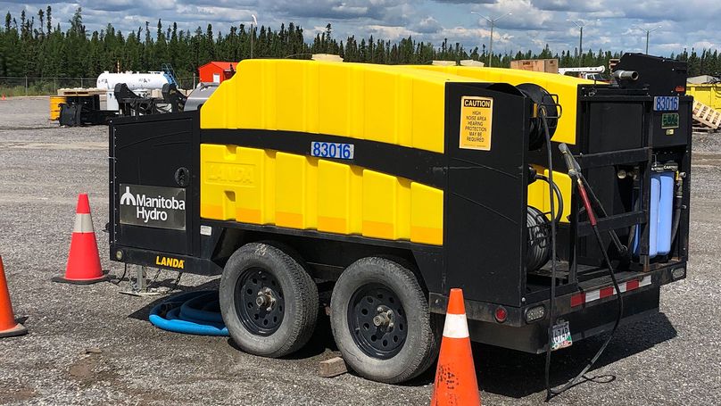 A black metal trailer, with a yellow plastic chamber for decontamination fluid, as well as several high pressure sprayers.