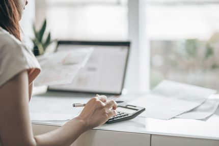 Woman using calculator with a document in her hand.