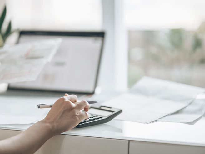 Woman using calculator with a document in her hand.