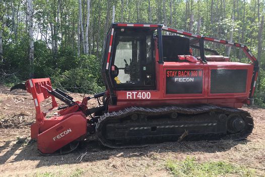 A tracked vehicle with a mulching attachment on the front used to clear vegetation along electrical infrastructure.