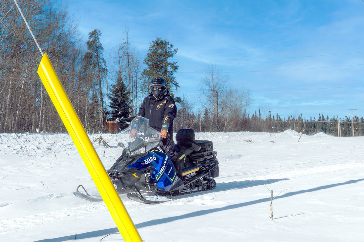 A snowmobile approaches a guy wire